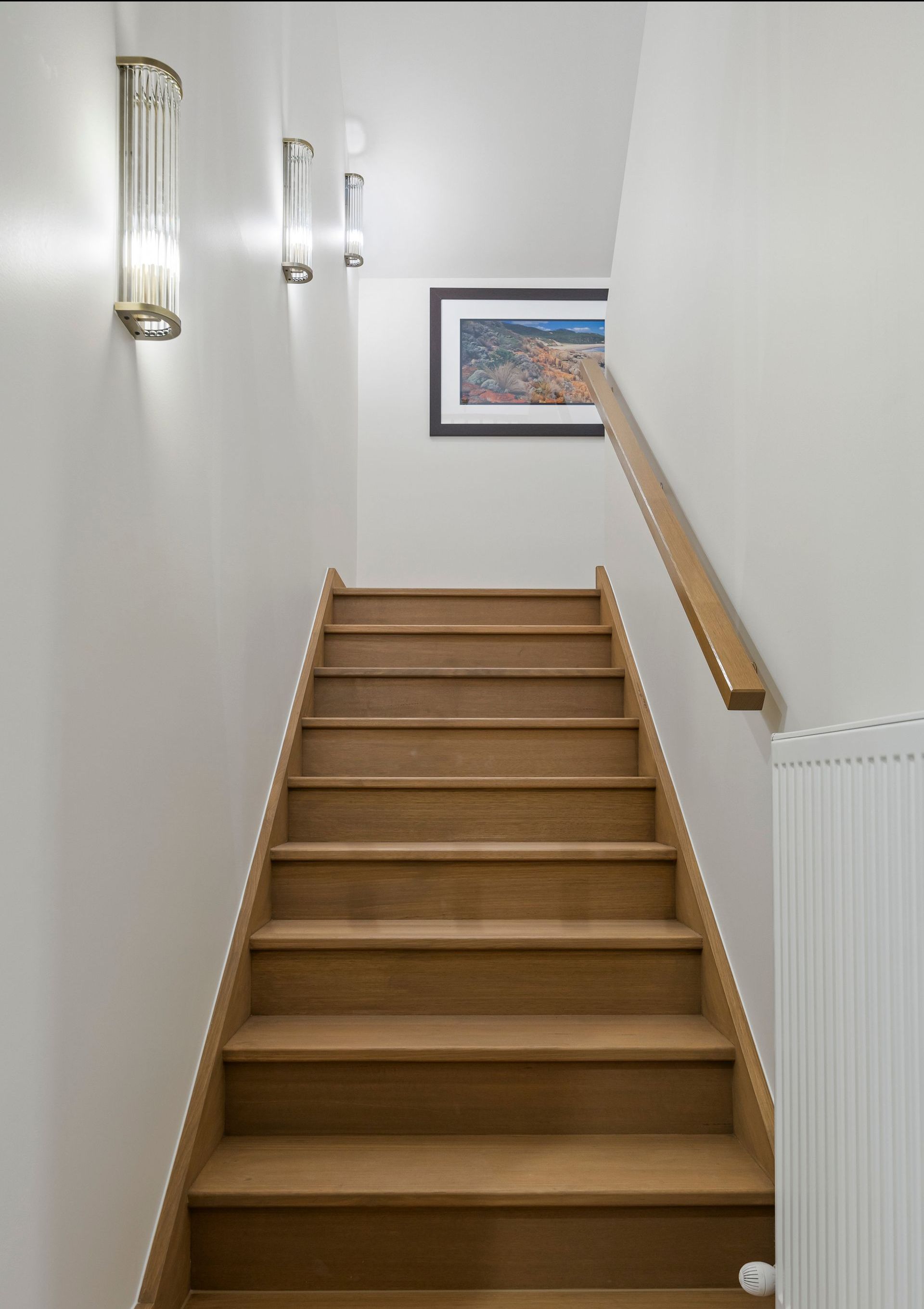 Timber staircase with minimalist lighting and framed art