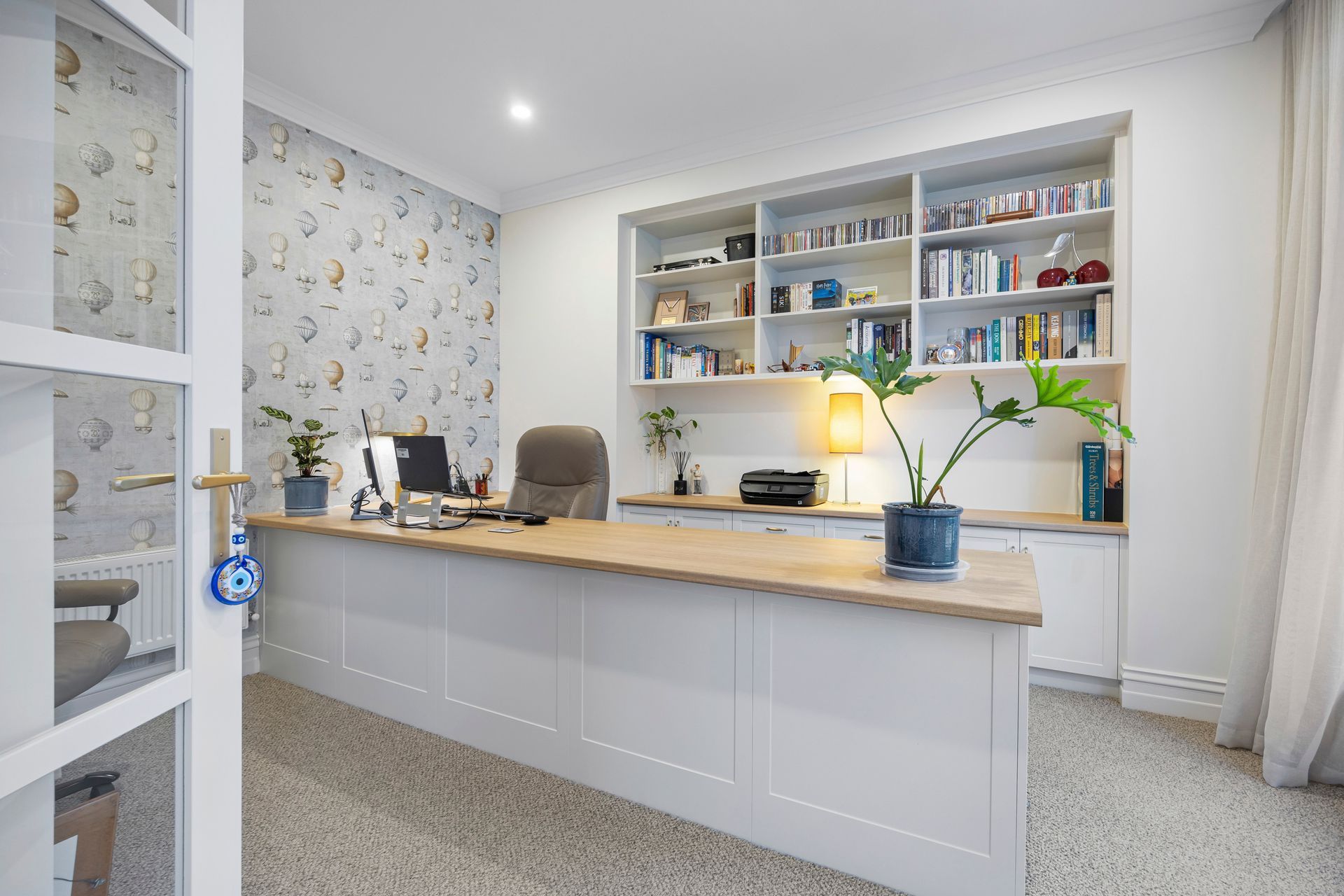 Dual-desk workspace with white joinery and wallpaper feature