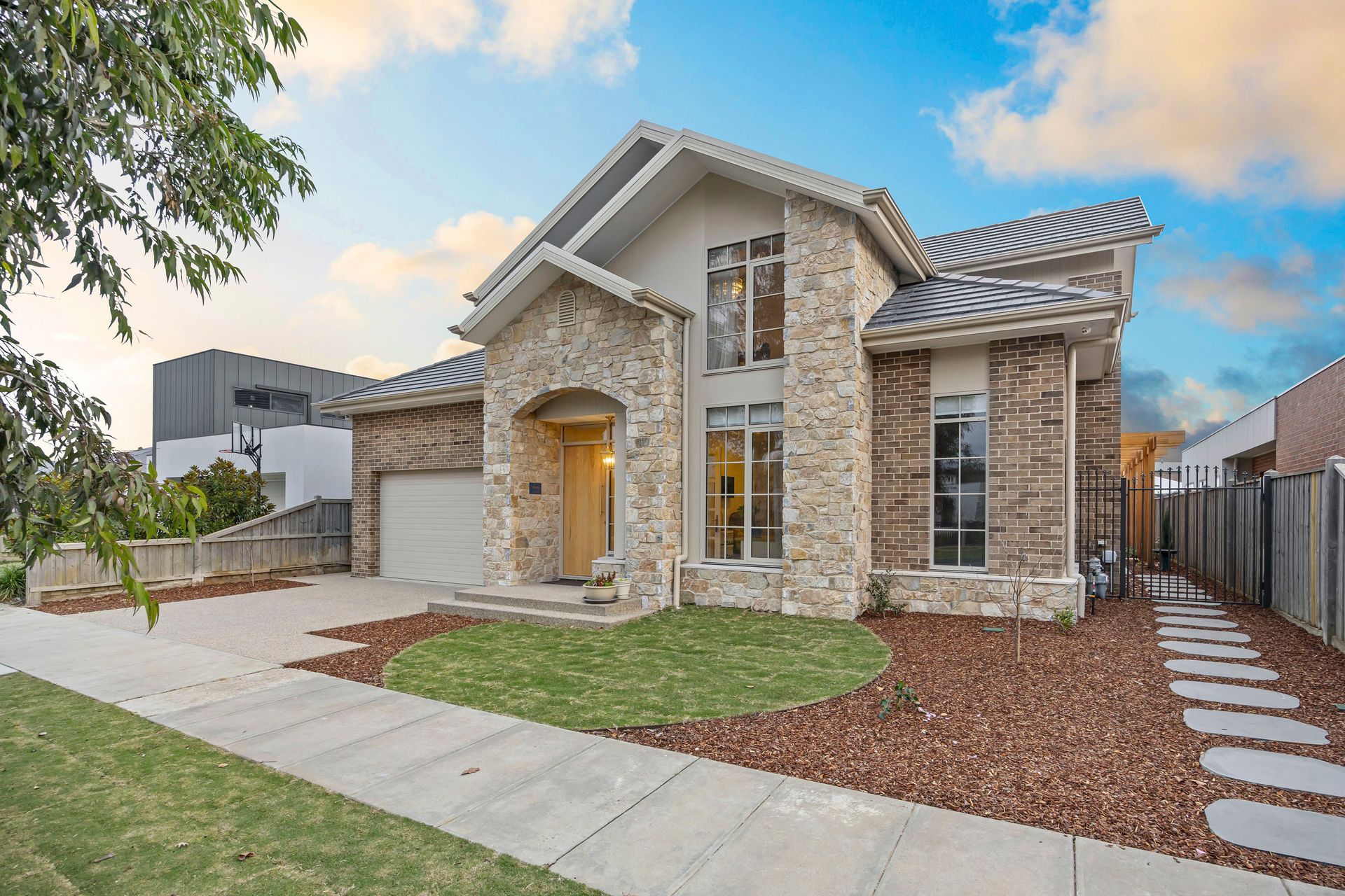 Stunning front elevation with brick and stone facade, gabled roofline and landscaped garden