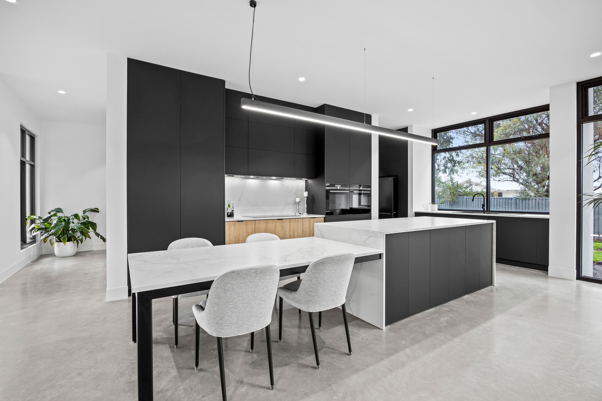 Modern monochrome kitchen and dining area with clean lines and large windows.

