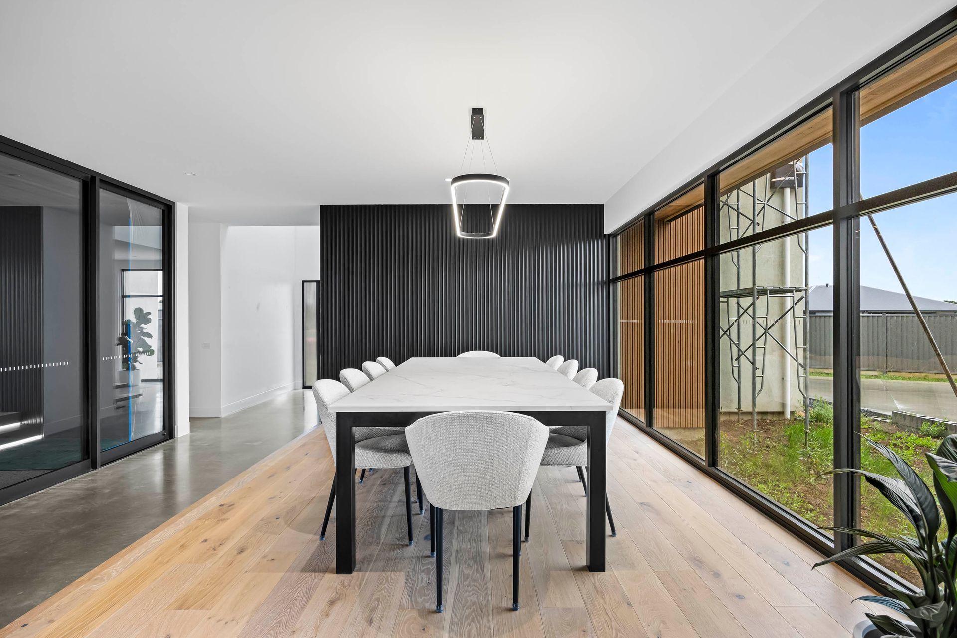 Bright dining room with floor-to-ceiling windows and timber flooring.
