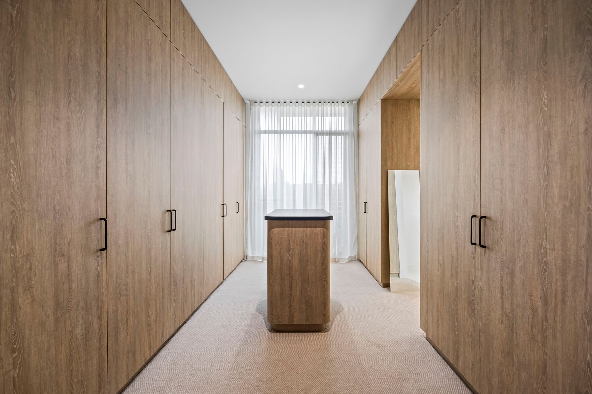 Walk-in robe with full-height timber cabinetry and soft lighting.
