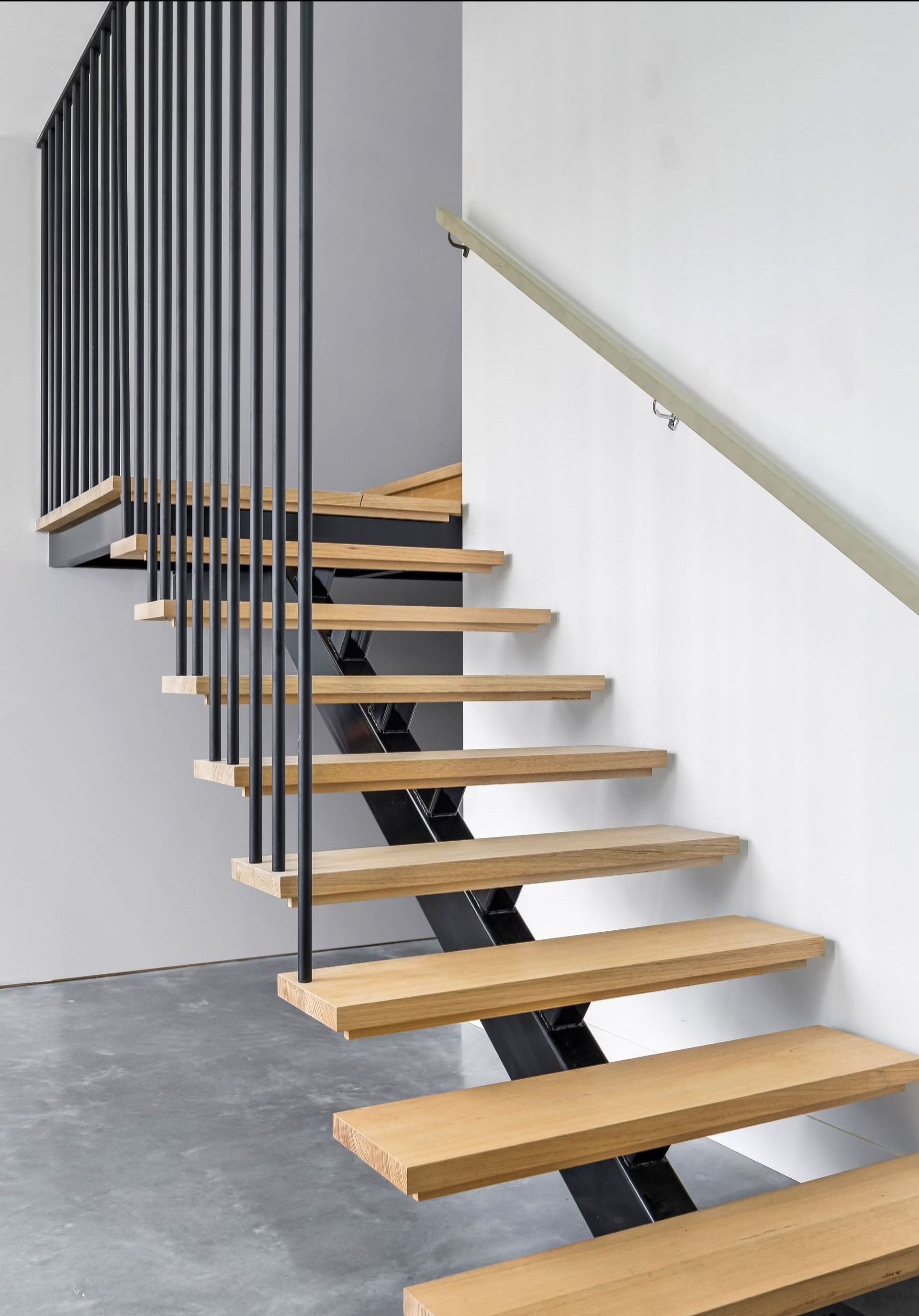 Architectural timber staircase with black vertical balusters and floating treads.
