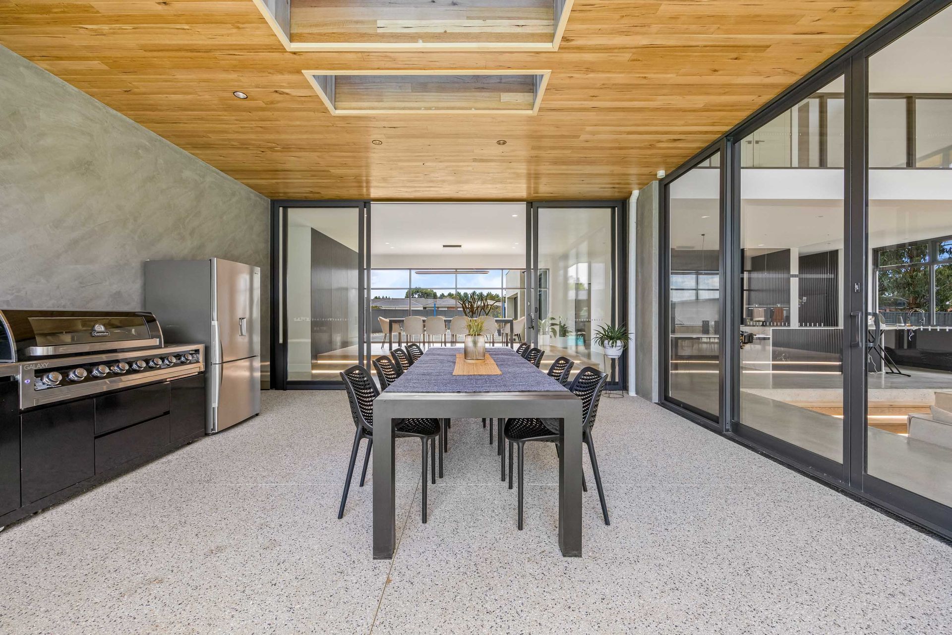 Covered alfresco dining area with built-in barbecue and skylight ceiling.