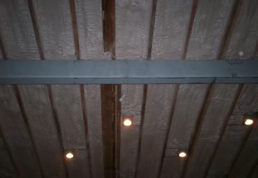 Underside of a metal roof with gray beams and several small round lights