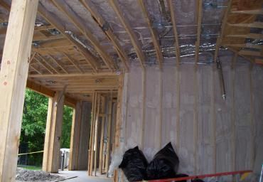 Partially finished room with exposed wood framing, insulation, and a window opening