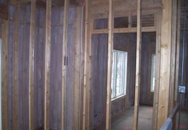 Unfinished interior with exposed wood framing and open doorway in a framed room.