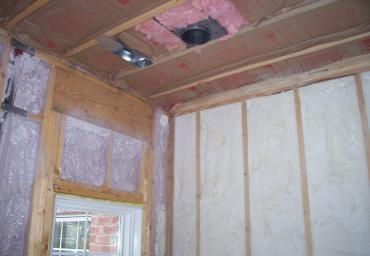 Interior room under construction with exposed wooden studs, insulation, and unfinished ceiling openings