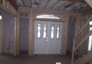 Unfinished wooden room with white double doors and narrow windows under a vaulted ceiling