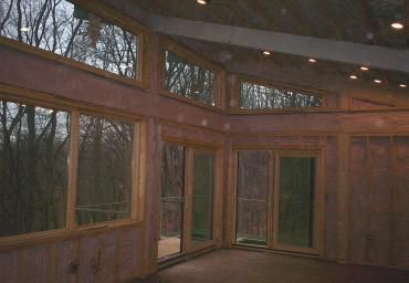 Wood-paneled room with floor-to-ceiling windows overlooking a wooded forest