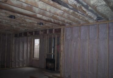 Unfinished basement room with exposed wood framing, insulation, and a small window.