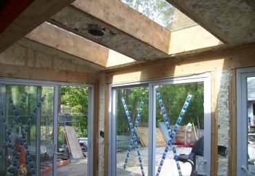 Unfinished room with concrete beams and large glass doors opening to a patio and garden.