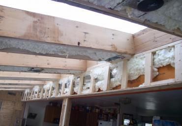 Interior under construction with exposed beams and insulation between ceiling joists