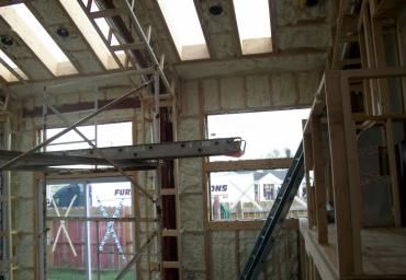 Interior of a construction site with exposed beams, scaffolding, and unfinished walls