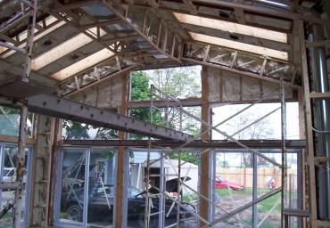 Interior of a house under construction with exposed wooden framing and roof trusses