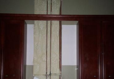 Dark wooden cabinets with a narrow striped curtain hanging between them.