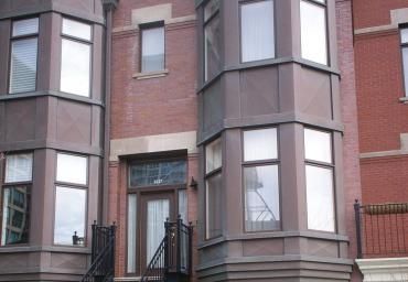 Brick townhouse facade with bay windows and a black front door