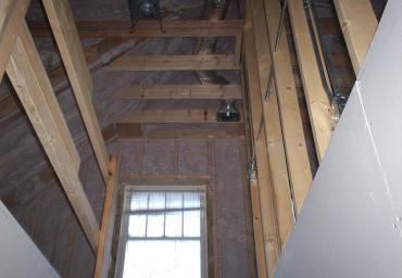 Unfinished attic or hallway with exposed wooden beams and a window at the end