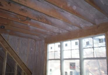 Wooden interior with slanted ceiling and large window letting in bright daylight