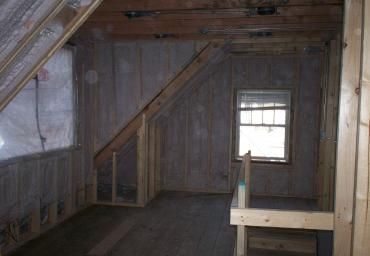 Empty wooden attic room with slanted ceiling and small window