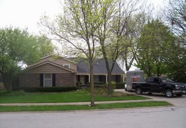 Suburban house with a front yard, leafless tree, and a black pickup truck parked in the driveway.