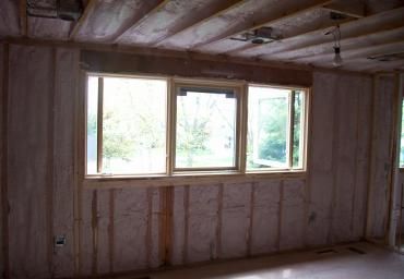 Bare unfinished room with exposed insulation and a small row of windows letting in daylight