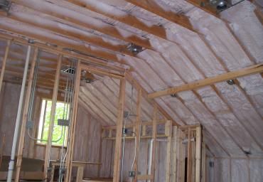 Insulated attic under construction with exposed wooden framing and roof trusses
