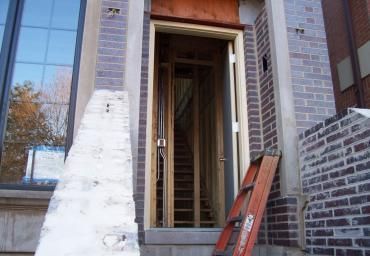 Building entrance under construction with a ladder and unfinished brickwork