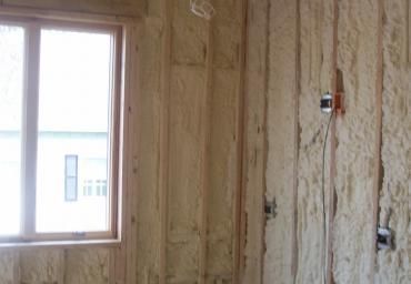 Unfinished room with exposed insulation and a window letting in daylight