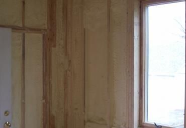 Unfinished wood-paneled interior wall with a window showing bright snowy outdoors