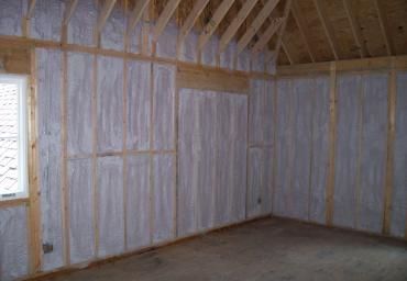 Unfinished room interior with exposed wooden framing and insulated walls, viewed from a corner.
