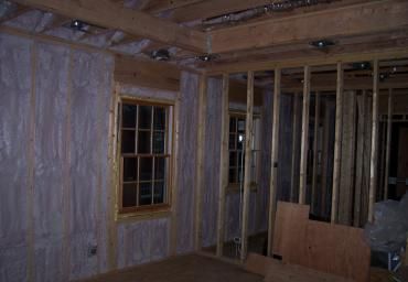 Unfinished room framed with exposed wood studs, insulation, and windows