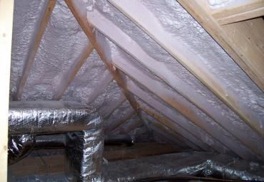 Insulated attic with silver reflective foil and exposed wooden rafters