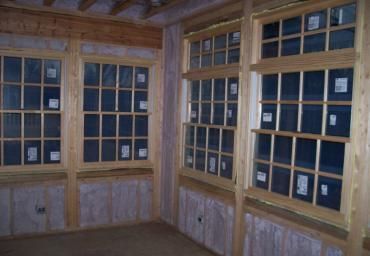 Wood-paneled room with corner windows and rows of framed photos or plaques behind glass