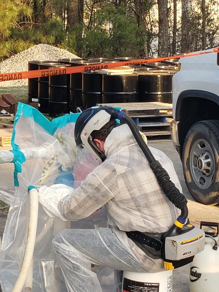 A man working on asbestos abatement is sitting on a bucket in front of a truck.