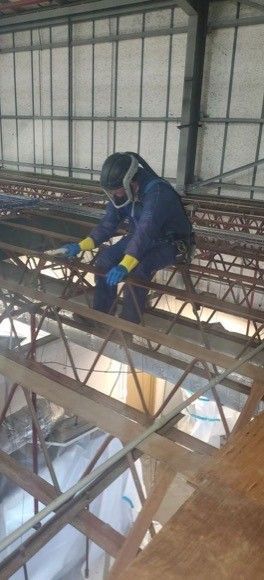 A man is welding a metal structure in a building.