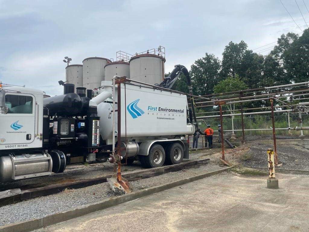 A white First Environmental truck is parked next to a train track.