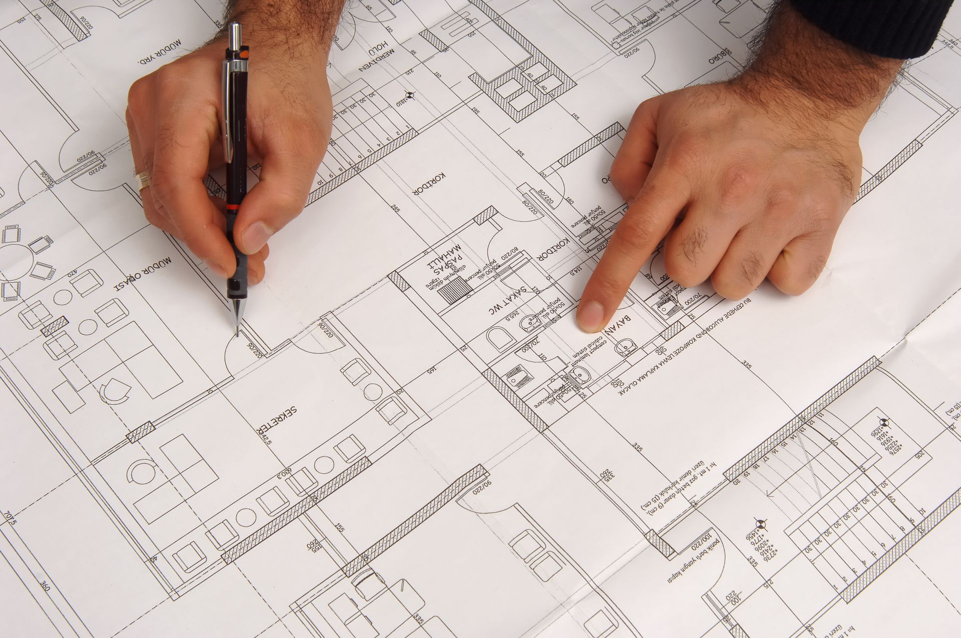 Mani che disegnano e indicano i dettagli sui progetti architettonici.