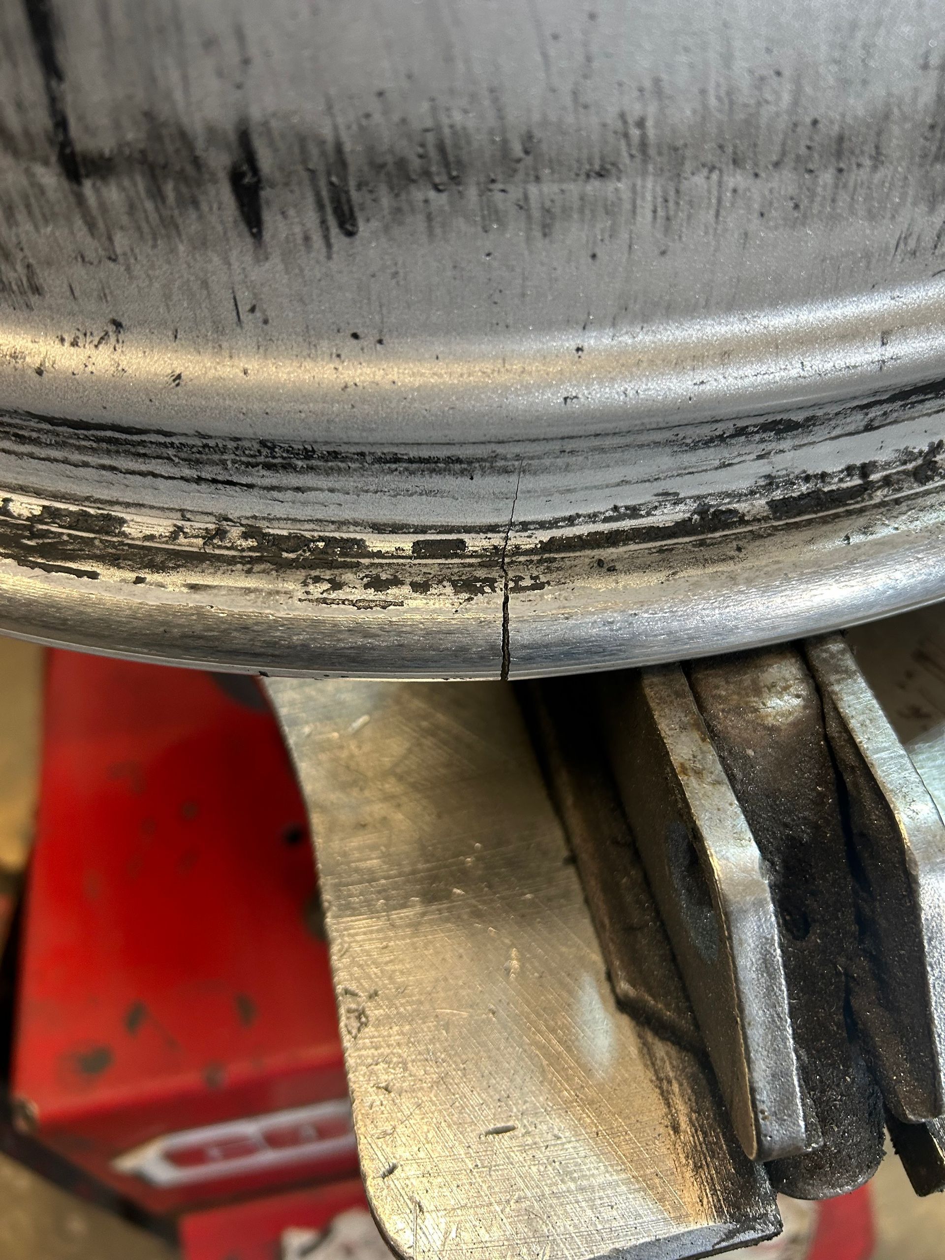 Close-up of a dirty metal wheel rim and brake assembly with grease and grime.
