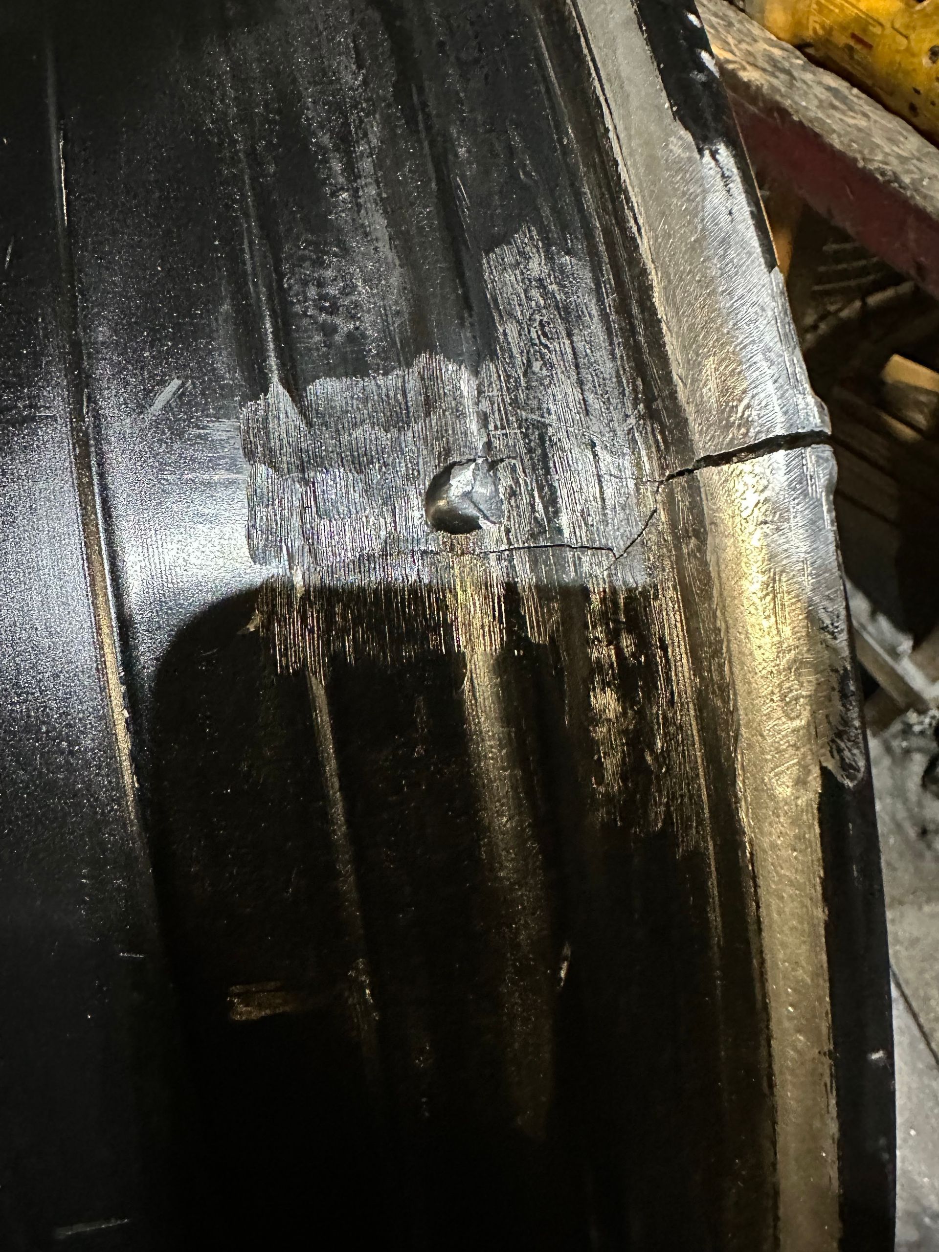 Close-up of a wet black car wheel arch with water streaks and a muddy tire.