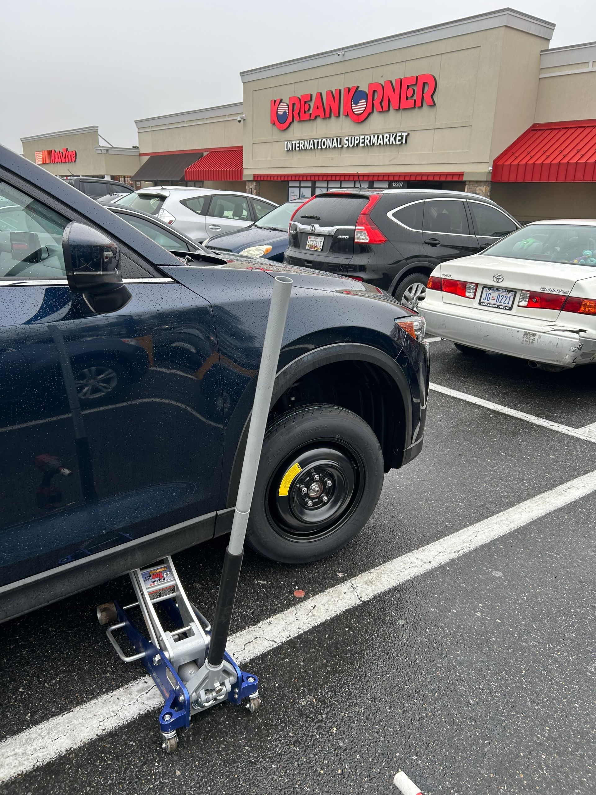 Disabled parking sign beside a dark blue SUV in a store parking lot, with Cabela’s in the background