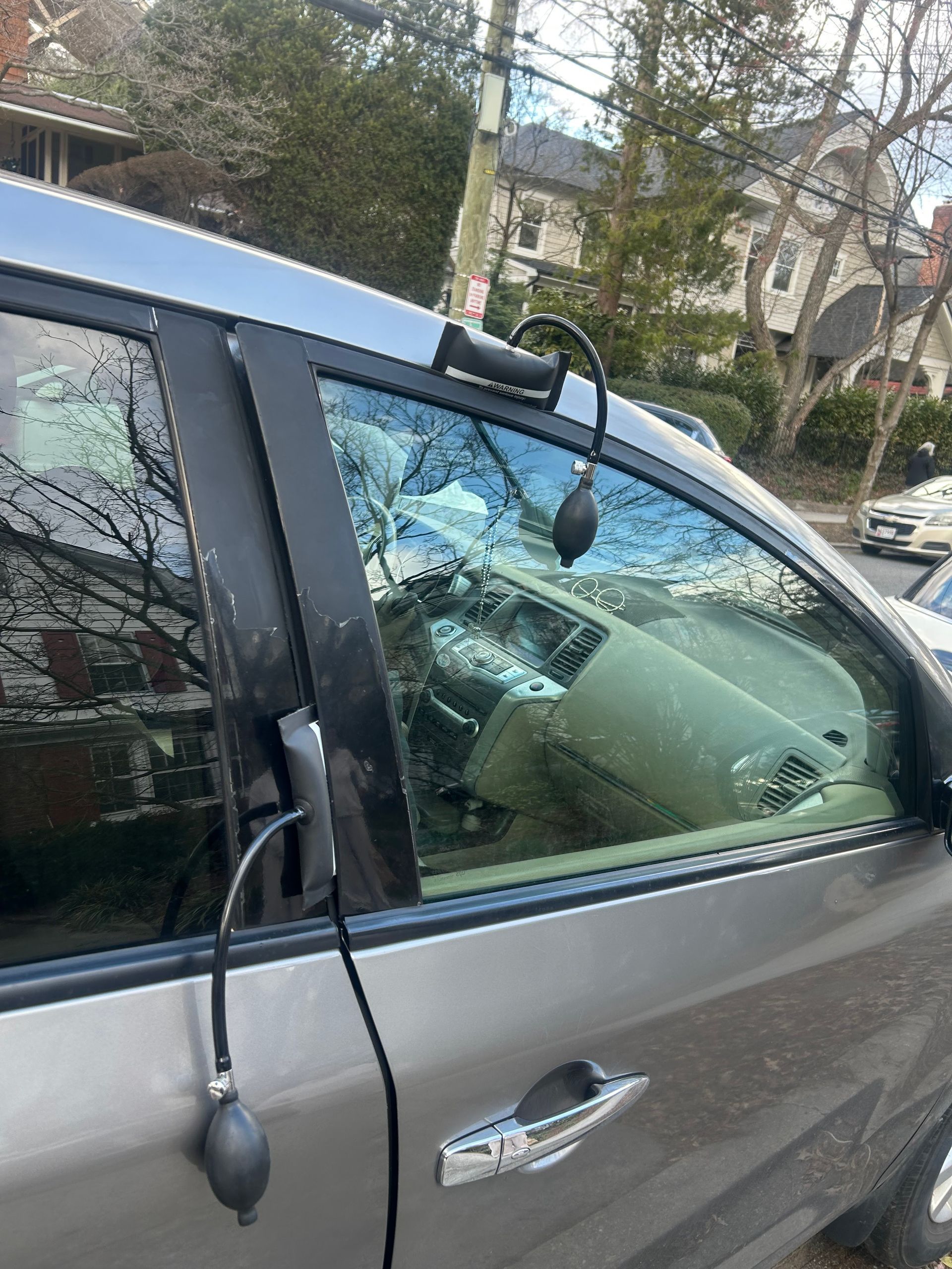 Damaged car door and shattered window with hanging side mirror on a gray vehicle street side