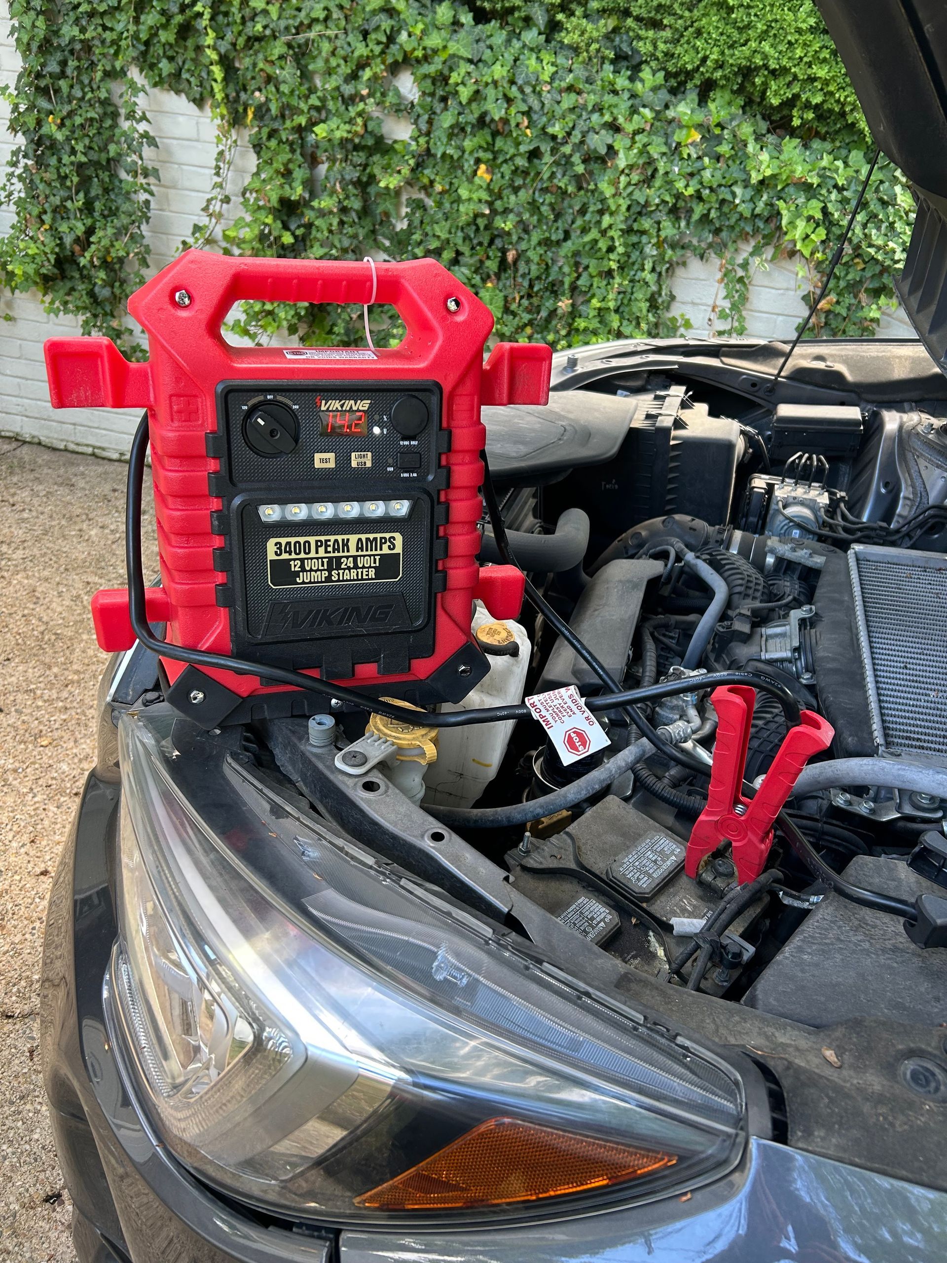 Red jump starter on a car battery in an open engine bay