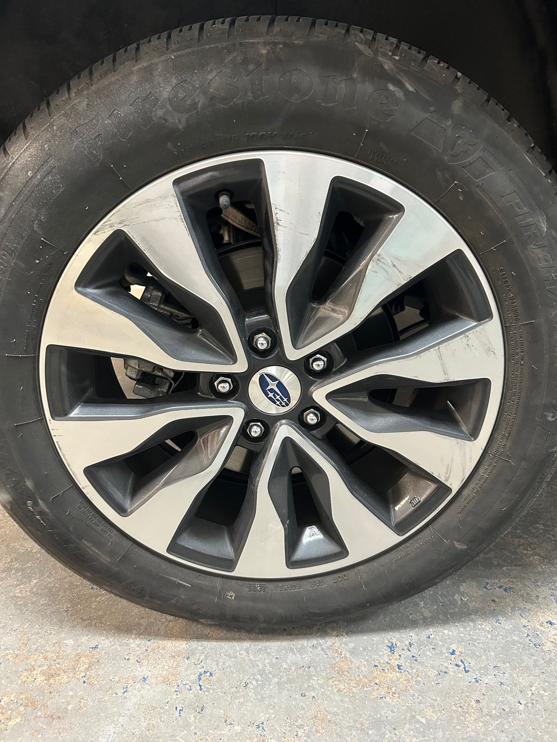 Close-up of a dirty car tire and alloy wheel on pavement
