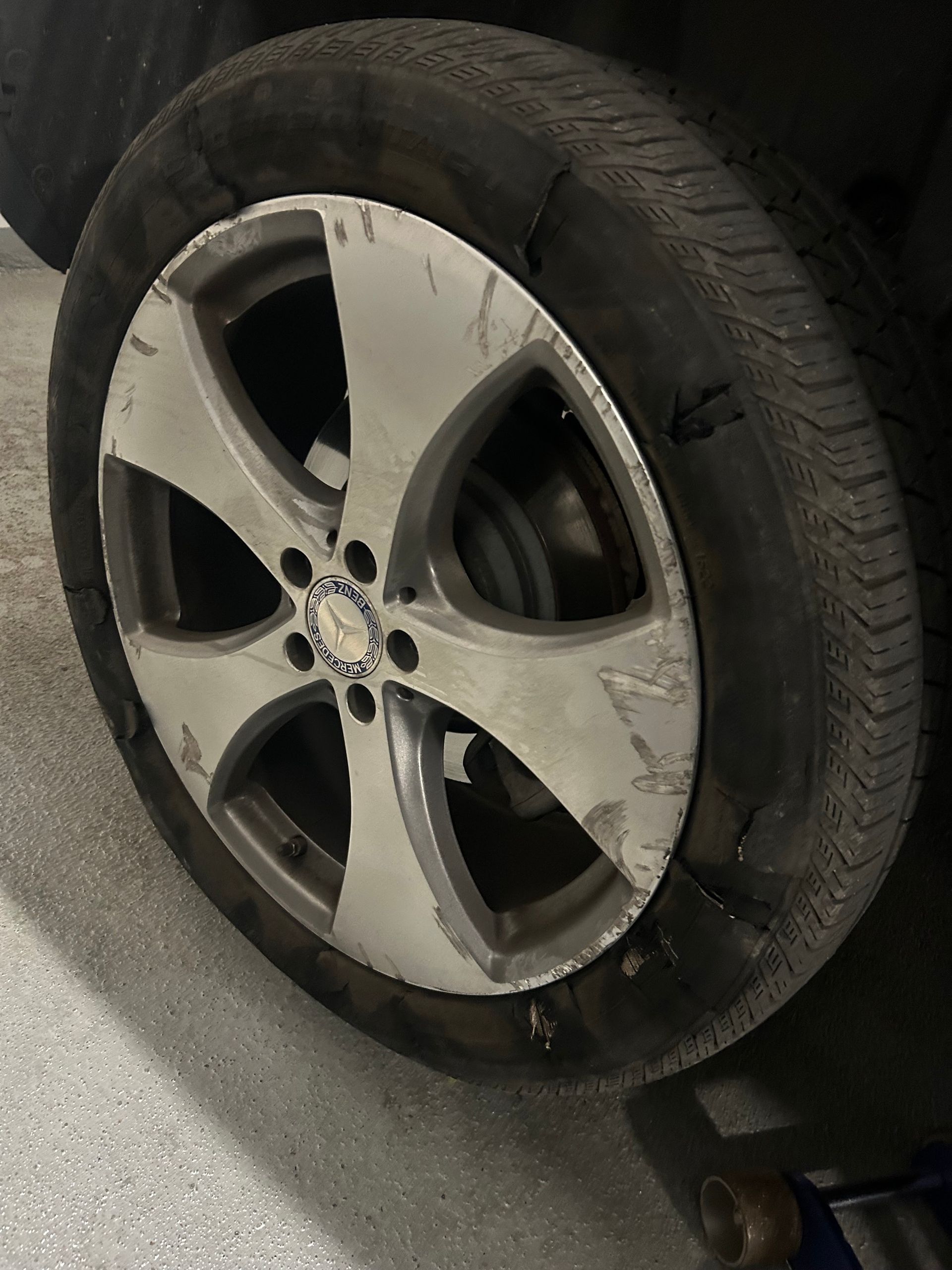 Damaged car wheel with a flat tire and scratched silver rim