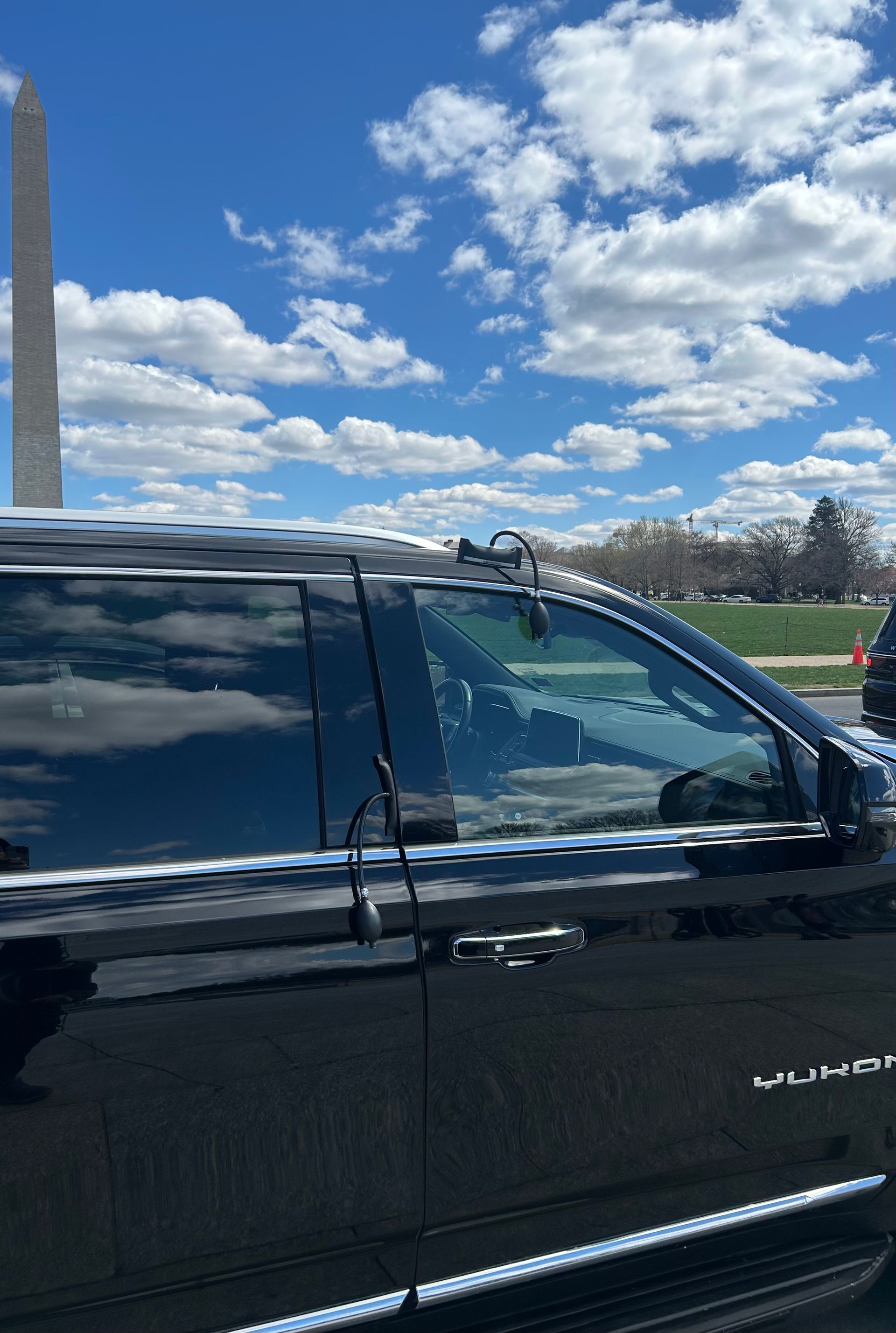 Black SUV parked outdoors under a bright blue sky with clouds