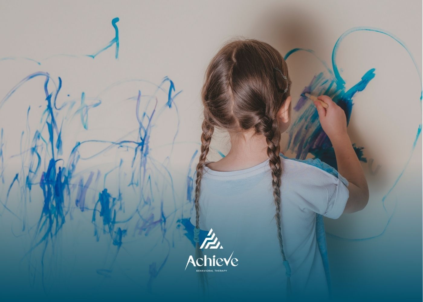 Girl with pigtails painting on a wall with blue paint.