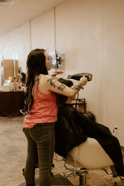 Professional hair stylist blow-drying a client’s hair at The Girl House salon in Springfield, MO.