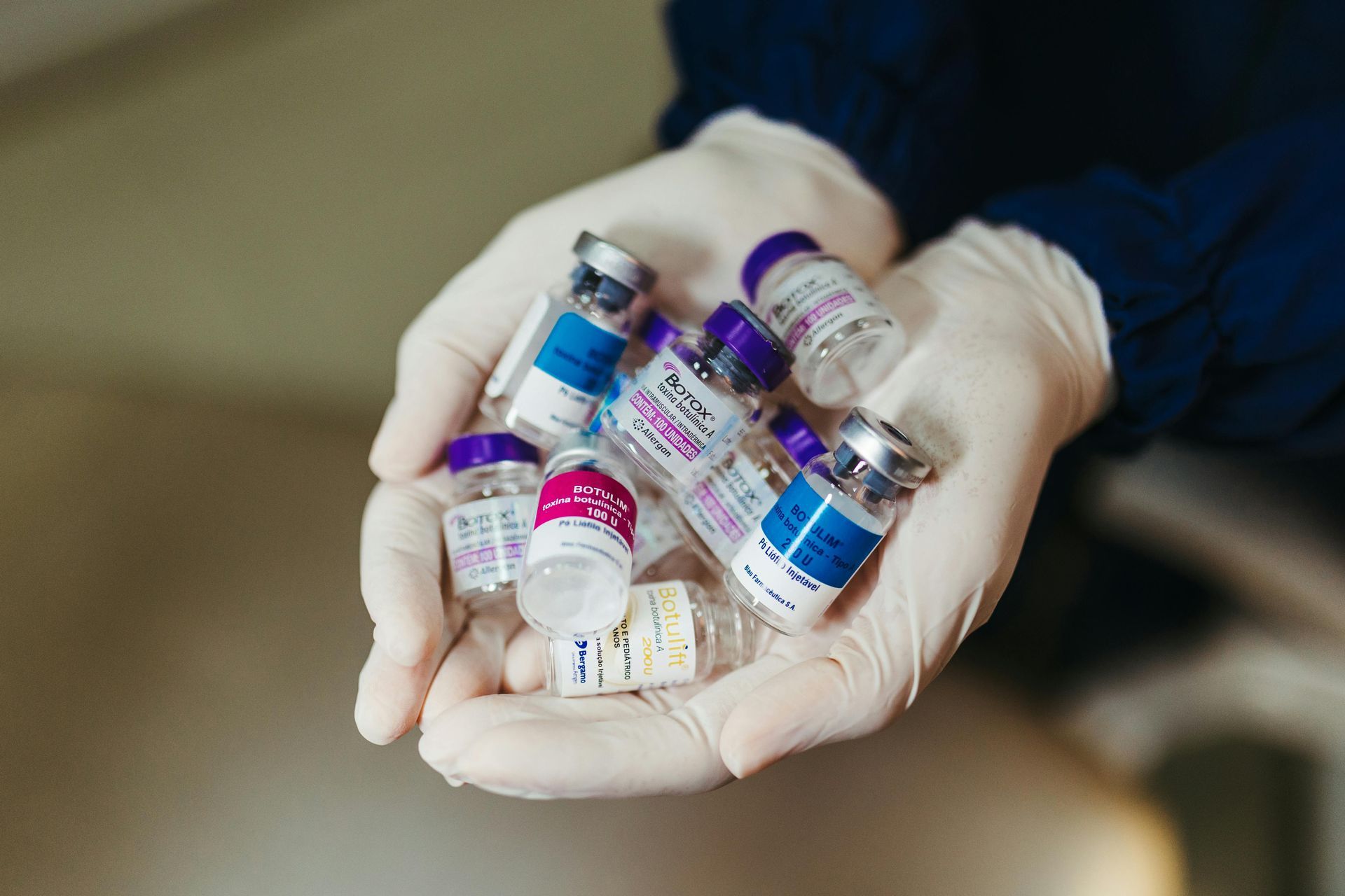 Gloved hands holding vials of cosmetic injectable products