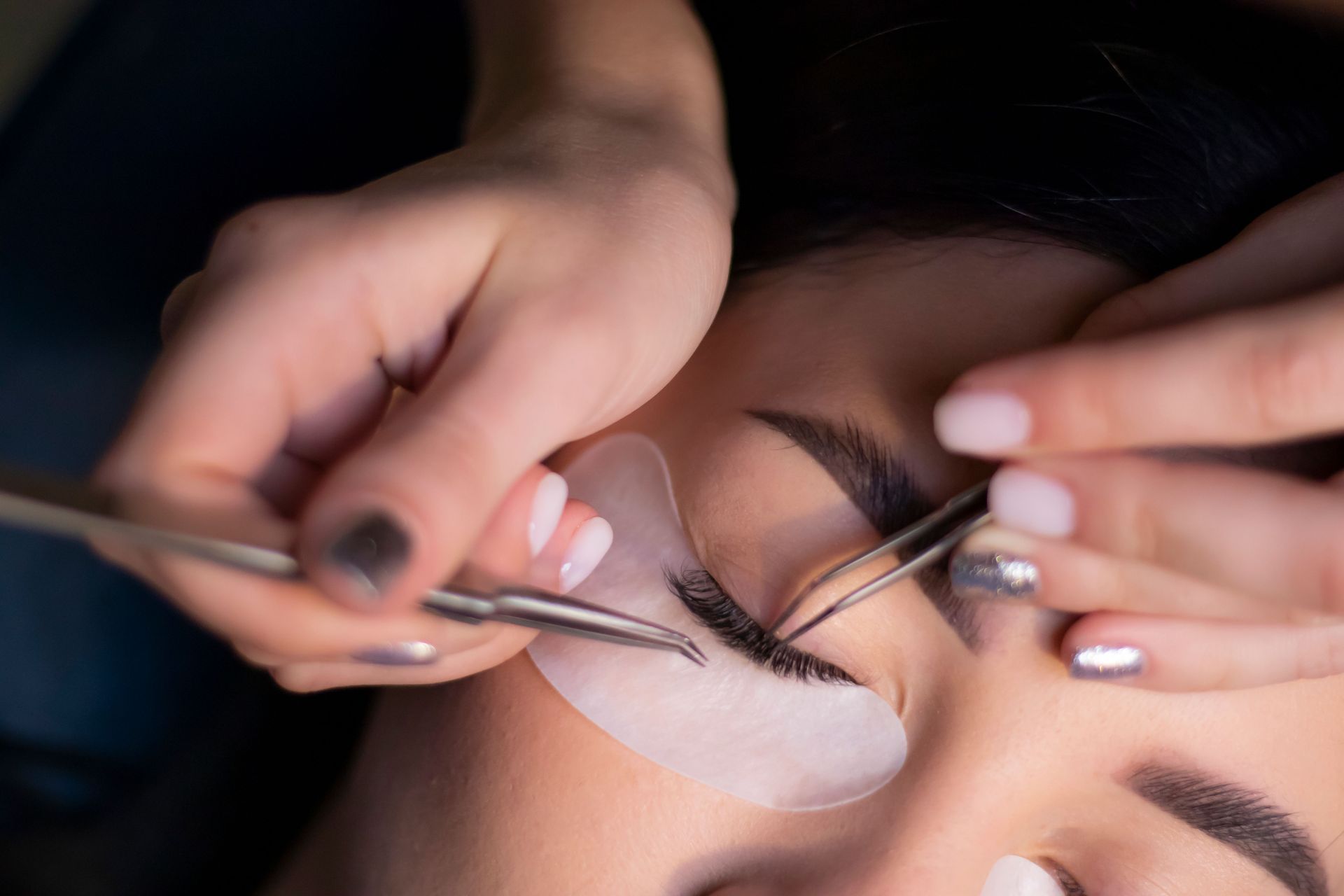 Lash artist applying eyelash extensions to a client during a beauty appointment near Nixa, MO.